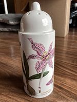 Side view showing botanical floral design on white ceramic body of flour shaker