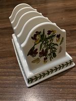 Side view showing botanical floral design with pansies in purple and yellow, and green leaf vine border on base.