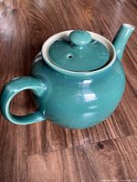 Top and side view of the vintage Sadler green ceramic teapot with smooth round handle and spout on a wood surface.