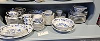 Wide shot of the Blue Danube China dinnerware set showing various plates, bowls, cups, saucers, creamer on a shelf.