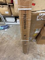 Tall rectangular cardboard box containing the projector screen, labeled with model number PRJSM9406.