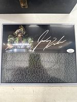 Full view of signed photo in plastic sleeve on white surface