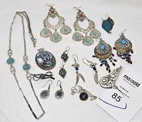 Full view of all jewelry items laid out showing necklaces, multiple pairs of earrings, brooch, and pendants with a variety of stones and silver metalwork.