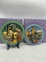 Two Disney collectible plates displayed with their original purple patterned boxes, depicting characters from Lady and the Tramp.