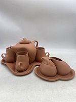 Full set arranged showing teapot, four mugs, creamer and sugar on separate trays