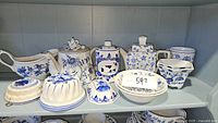 Full shelf view showing various blue and white ceramic china pieces including teapots, bowls, plates, and decorative jars