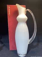 Full view of Orrefors white glass vase pitcher standing beside its original red box.