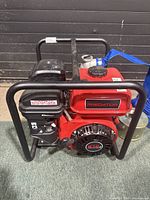 Full side view of the Predator 212cc engine pump showing the black metal frame, red engine, and hose attachments.