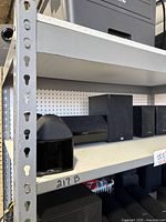 Overview of shelf showing four Mirage satellite speakers, one Realistic center channel speaker, and one Dual bookshelf speaker