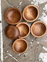 Set of six wooden salad bowls arranged with some turned to show the inside and one turned to show the underside.