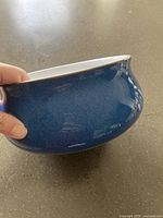 Side view of blue casserole pot with a glossy mottled finish held in hand