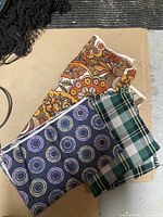 Three fabric pieces displayed showing different patterns: floral, plaid, and circular design.