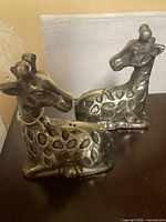 Metal giraffe-shaped salt and pepper shakers shown side by side, highlighting the design and texture.