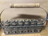 Full view of the six clear glass vases arranged in the metal carrier with a wooden handle, showing the size and overall design.