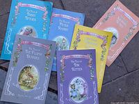 Six Beatrix Potter jumbo-sized books with decorative covers arranged on ground.