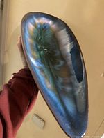 Oblong pottery decor piece showing glossy blue-green tones with natural flowing glaze pattern.