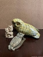 Set of four owl figurines including a large painted owl, small carved pair, silver metal dish and brass clip