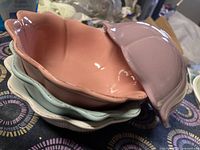 Stack of four ceramic petal bowls in pastel colors including pink and blue, showing the shape and condition.