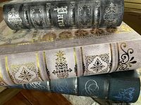Close-up of the spines of three decorative book storage boxes featuring elaborate Parisian designs and the word 'Paris'