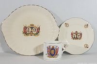 Set of three royal collectible ceramics including one cup and two plates, featuring King George VI and Queen Elizabeth from 1937 to 1939.