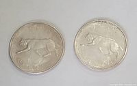 Two 1967 Canada Centennial quarters showing the bobcat design on the reverse sides.