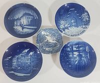Top-down photo of all five plates and dishes arranged closely together, showing detailed blue and white winter and holiday scenes on each piece.