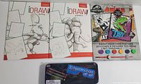 Photo showing multiple items including 3 iDraw! drawing books, Jurassic World Paint Your Own Posters kit, and 3D Hypotrochoid art set