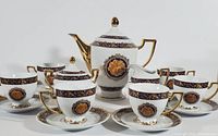 Front view, showing teapot, two teacups and their saucers, sugar bowl, and creamer with ornate blue and gold detailing.