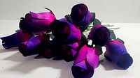 Twelve wooden roses painted in fuchsia and purple shades, showing detailed colors and leaves.