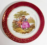 Full view of Limoges France decorative plate featuring Fragonard courting couple portrait and red gold-gilded border.