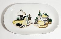 Full view of the vintage Kahla German Democratic Republic platter showing the painted cheese, oil lamp, and wine bottle design.