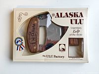 Front view of the Alaska ULU knife packaged inside a display box with window showing wooden handle and blade.