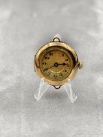 Front view of an antique gold filled wristwatch with a round dial showing Arabic numerals and smaller subdial for seconds, with visible wear and patina on case.
