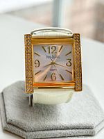 Front view of Joan Rivers Classics quartz women's wristwatch with gold-tone rectangular case, crystal embellishments on case sides, white dial with gold-tone numerals and hands, and white crocodile-embossed leather strap.