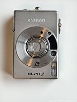 Front view of the silver Canon ELPH2 film camera showing lens, flash, and branding.