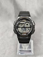 Casio AE-1000W watch front full view showing watch face, rubber strap and digital display with world time and alarms.