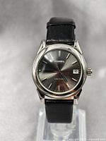 Front view of the Fossil Arkitekt watch showing black sunburst dial, date display, and black leather strap.