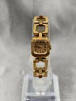 Front view of Seiko ladies gold plated mechanical watch on stand showing square face and bracelet links.