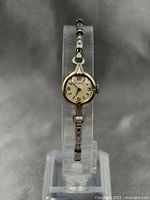 Full view of the vintage ladies wristwatch on display stand showing gold plated linked bracelet and round watch face.