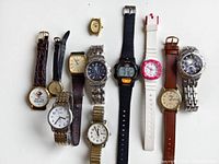 Top-down view of all 10 watches showing different styles, face shapes, and band materials and colors.