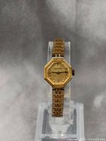 Full view of the vintage Bulova ladies watch on display stand showing gold-tone hexagonal case and linked bracelet