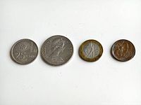 Four vintage coins side by side laid flat on white background for overview of lot contents.