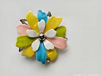 Top-down view of the vintage Sarah Coventry enamel flower brooch showing multi-colored petals and central silver ball.