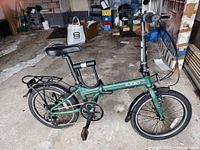 Full left-side view of green Zizzo folding bike with U-lock on seat tube