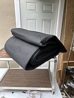 Rolled black garage floor pad on metal shelf in front of a door.