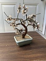 Front view of the artificial bonsai tree showing white glass shells, bonsai trunk, and celadon pot.