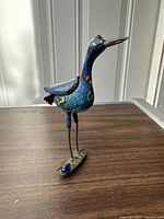 Front and side angled view of cloisonné heron bird incense burner showing blue and green enamel decoration and metal base.