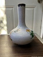 Photo showing the front side of the Chinese cloisonné vase with white birds and flower motifs on a geometric patterned background.