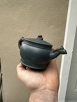 Side angle of the handmade Yixing Zisha teapot showing dragon spout and handle, and round body.