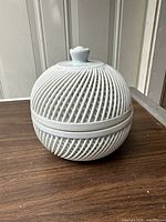 Full view of the complete covered dish showing woven spiral pattern over the entire round form with knob lid.